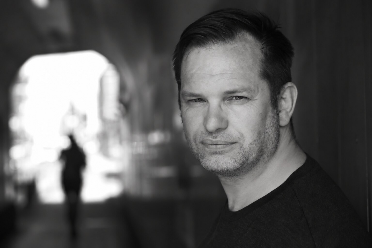 Black-and-white portrait of Phil Gwilliam in an urban passageway